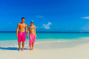 Wall Mural - Couple at the beach, standng on the beach with pink outfits