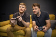 © Model Republic - male homosexual couple passionately playing video games holding console joysticks. focused gays emotionally clicking fast control buttons gamepad sitting on comfy sofa. LGBT family Resting At Home