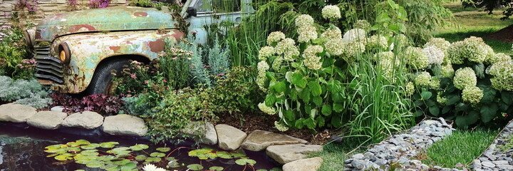 Modern Landscaped Backyard Garden with Small Artificial Pond from PVC and Old Car as Designed Element. Modern Garden at House with Stony Landscaping  Retro Style with Decorative Pond and Old Car.