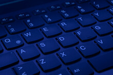 QWERTY Keys Of A Laptop Computer Keyboard Illuminated With Uv Ultraviolet Purple Light