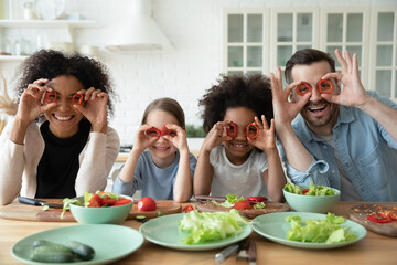 Wall Mural - Portrait of happy multiethnic family with little diverse daughters have fun cook in home kitchen together. Smiling multiracial mom and dad preparing food with ethnic children. Diversity concept.