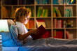 © famveldman - Child reading book in bed. Kids read at night.