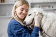 Happy female veterinarian hugs the patient big white dog standing at examination table after inspection. Visit to the doctor. Pet care and check up. Close up.
