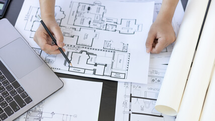 Architectural building design and construction plans with blueprints, Young man was designing a building or architecture with a ruler, pen, pencil, tape measure, architect hat and other equipment.