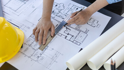 Engineer and Architect concept, Man uses a ruler to measure the floor plan on the blueprint, Building architecture design work, Construction design project under environmental conservation conditions.