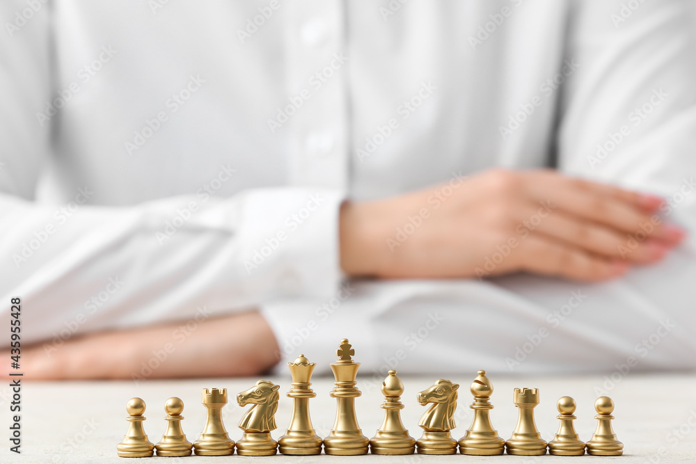 Woman and chess pieces on white table, closeup