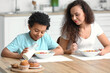 © Pixel-Shot - Little boy with mother eating cornflakes at home