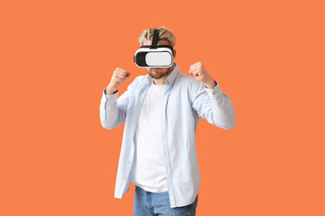Wall Mural - Young man with VR glasses on color background