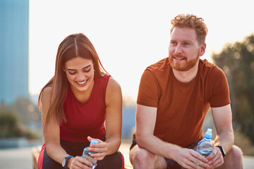 Two young sporty man and woman exercising in urban park.