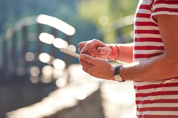 Young adult man using modern smartphone in the park.