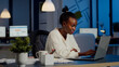 © DC Studio - Happy african freelancer reading tasks on laptop working overtime in start up company office. Enthusiastic employee owerworking late night respecting deadline of financial project