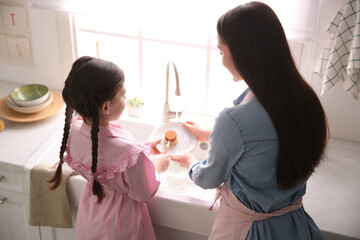 Canvas Print - Mother and daughter washing dishes together in kitchen