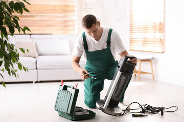 Poster - Professional technician repairing electric patio heater with screwdriver indoors