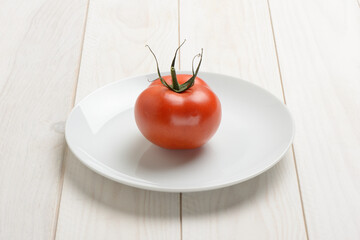 Tomate en un plato en la mesa blanca