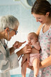 © NDABCREATIVITY - Pediatrician doctor medical examining little smiling baby, held by mother