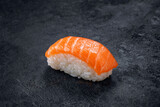 Fototapeta Maki - One nigiri sushi with salmon on a stone dark background. Japanese dish sushi of fresh fish