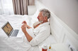 © Viacheslav Yakobchuk - Adult Caucasian man in white bathrobe talking with physician online while sitting on modern interior room