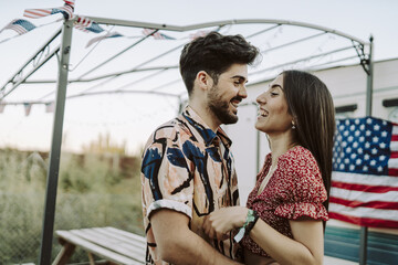 Beautiful Spanish couple laughing on background of US flags - US Independence day