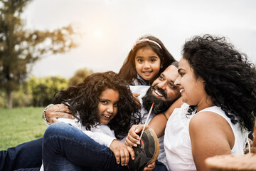 Wall Mural - happy indian family having fun at city park painting and laughing together - parents and children en