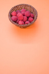 Poster - Vertical shot of a small basket with fresh raspberries isolated on a light-colored background