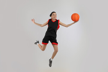 Wall Mural - Professional sportswoman playing basketball on grey background