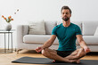 © LIGHTFIELD STUDIOS - man with closed eyes meditating in lotus pose on yoga mat