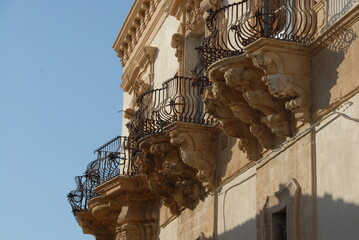 Wall Mural - The beautiful balconies of Palazzo Trigona in Noto  with curved iron railings, corbels in carved stone with grotesque figures such as mermaids, winged horses and angels.