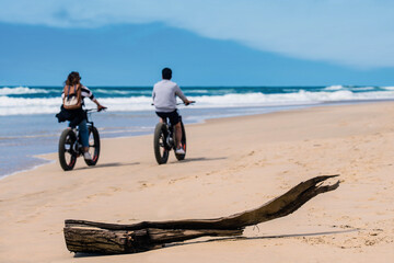 Wall Mural - couple riding bicycle or fat bike on sunny beach