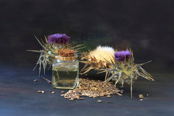 Wall Mural - Bottle of tincture or elixir essential oil and thistle flowers on wooden background.