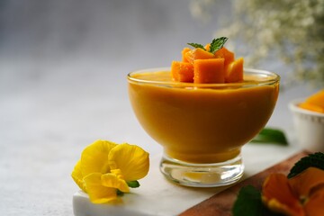 Wall Mural - Homemade Mango Mousse with cut mangoes and mint garnish, selective focus