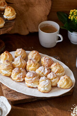 Sticker - Homemade profiteroles with powdered sugar. Side view, wooden background.