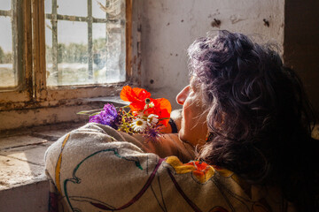 Sticker - Senior blue-haired female sitting near the window with beautiful flowers