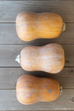 Three Butternut Squashes On Wooden Cutting Board Viewed From Above, Facing Opposite Directions