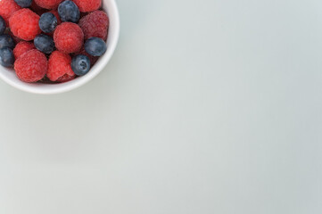 Wall Mural - Top view of fresh blueberry and raspberry on a white bowl