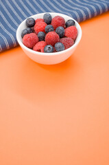 Canvas Print - Closeup shot of fresh blueberry and raspberry on a white bowl