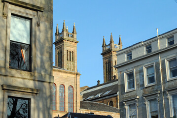 Wall Mural - Italienate Church Towers seen between Residential Buildings against Blue Sky 