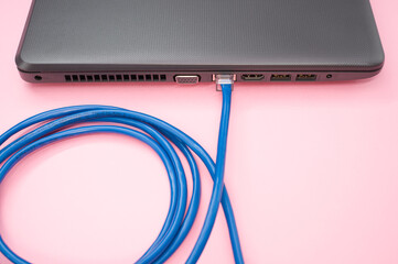 Sticker - Closeup of a LAN cable connected to a laptop isolated on a pink background