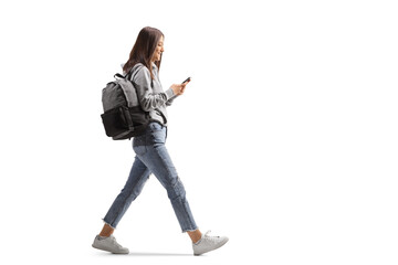 full length profile shot of a female student walking with a mobile phone