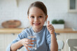 © fizkes - Portrait of happy little Caucasian girl child show thumb up recommend drinking clean pure mineral water. Smiling small kid follow healthy lifestyle enjoy clear still aqua. Habit, hydration concept.