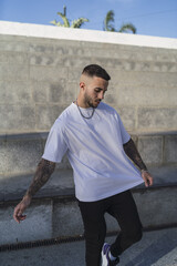 Poster - Spanish man with tattoos in casual style near stairs