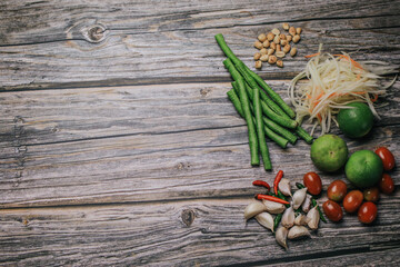 Wall Mural - Papaya salad (Som Tam) ingredients on wooden table background.The famous local Thai street food dish with the taste of hot and spicy.