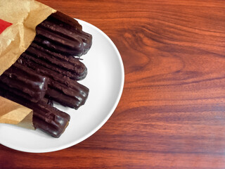 Canvas Print - churros covered with chocolate, traditional Argentine fried dough pastry. Wood background. Copyspace