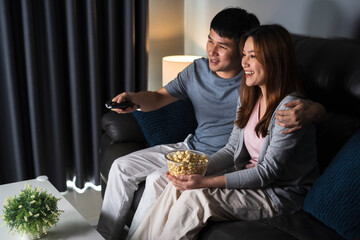 Wall Mural - happy couple watching TV on sofa at night