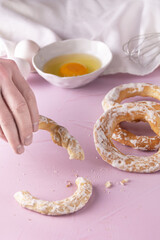 Sticker - Hand picking glazed bagels with eggs, egg beater, napkin on a pink surface