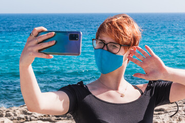 Poster - Young caucasian female in a face mask taking a selfie at the beach