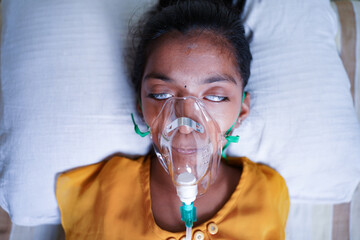 close up top view of young kid breathing on ventilator oxygen mask due to coronavirus covid-19 breat