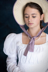 A young Regency woman wearing a white muslin dress and a straw bonnet