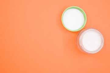 Sticker - Top view of cream on a cosmetic container isolated on an orange background