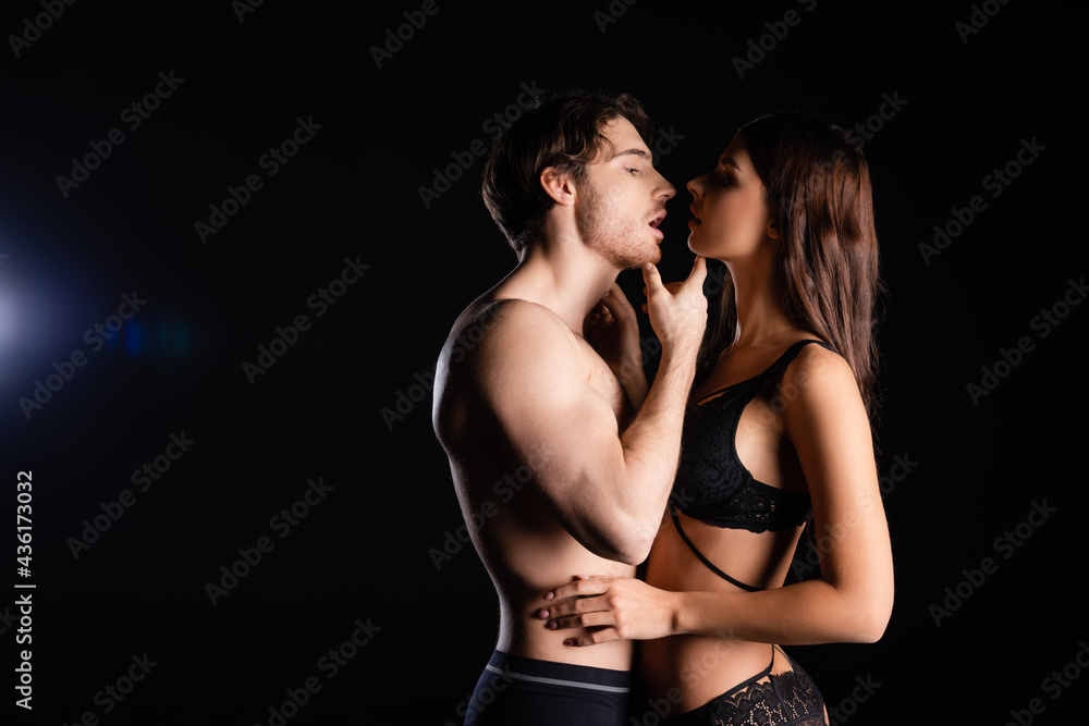 muscular man with shirtless torso gently kissing woman in lingerie on black  background Stock Photo | Adobe Stock