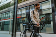 © bernardbodo - Handsome businessman texting on phone while out in the city with his bike